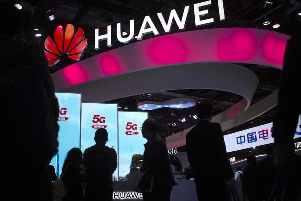 Attendees walk past a display for 5G services from Chinese technology firm Huawei.