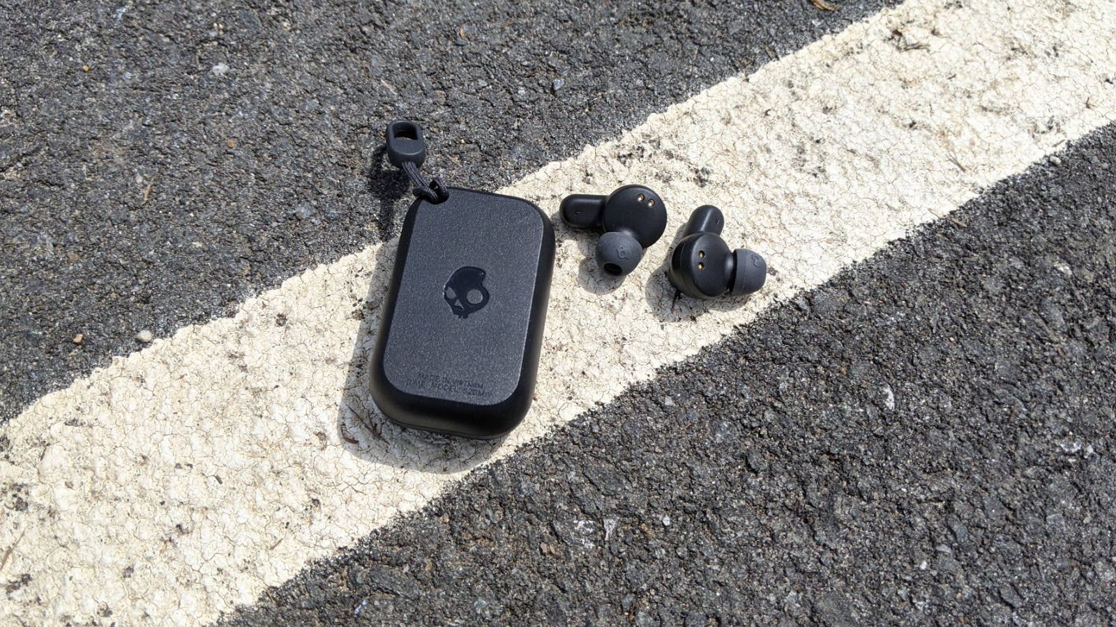 Casing Skullcandy Dime dan headphone terpisah di trotoar