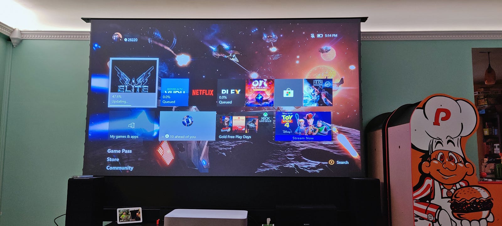 Một màn hình 100 inch khổng lồ hiển thị màn hình chính Xbox trong một căn phòng đủ ánh sáng.