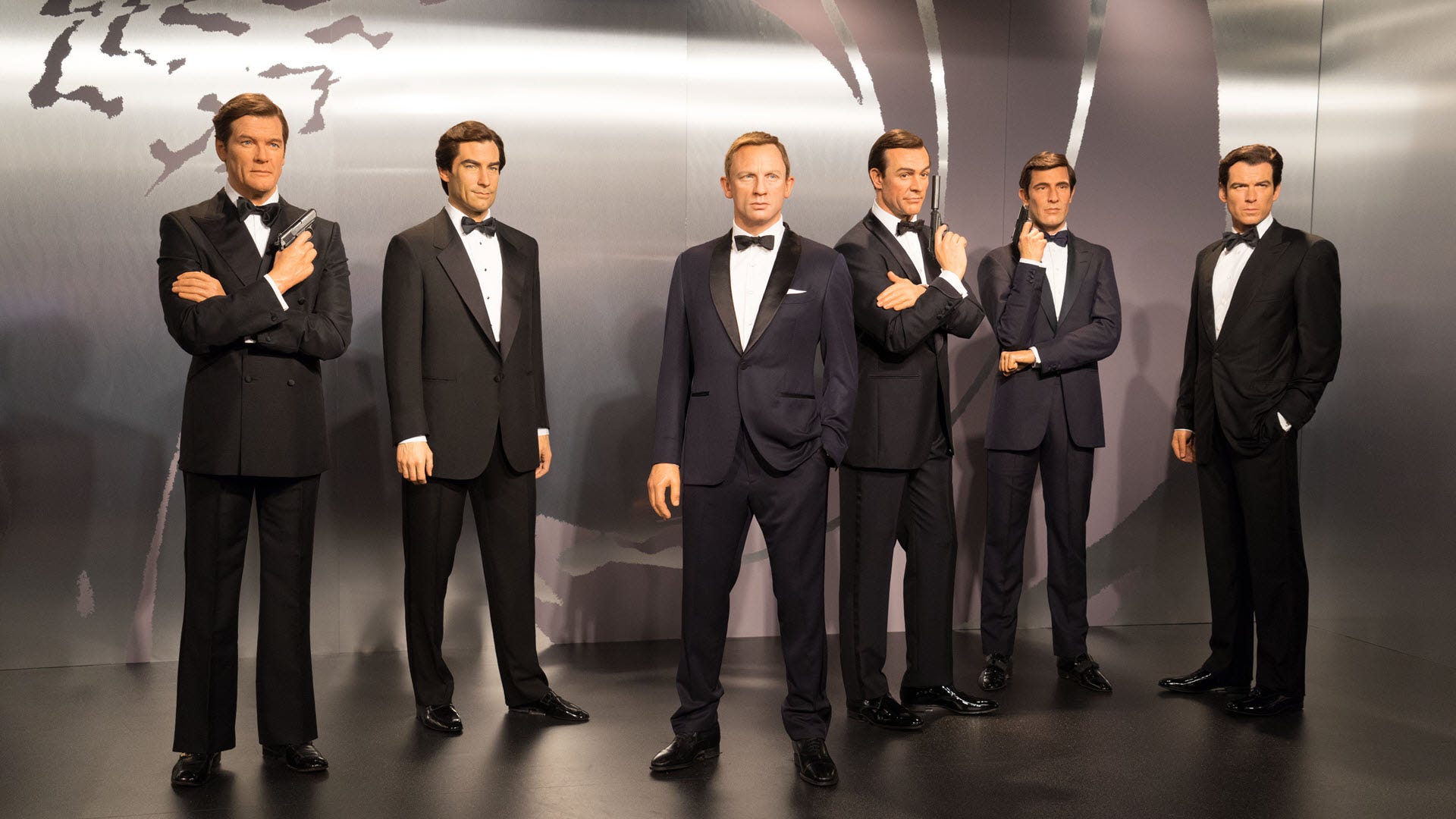 Tất cả các phiên bản khác nhau của James Bond đứng trước nền phim.