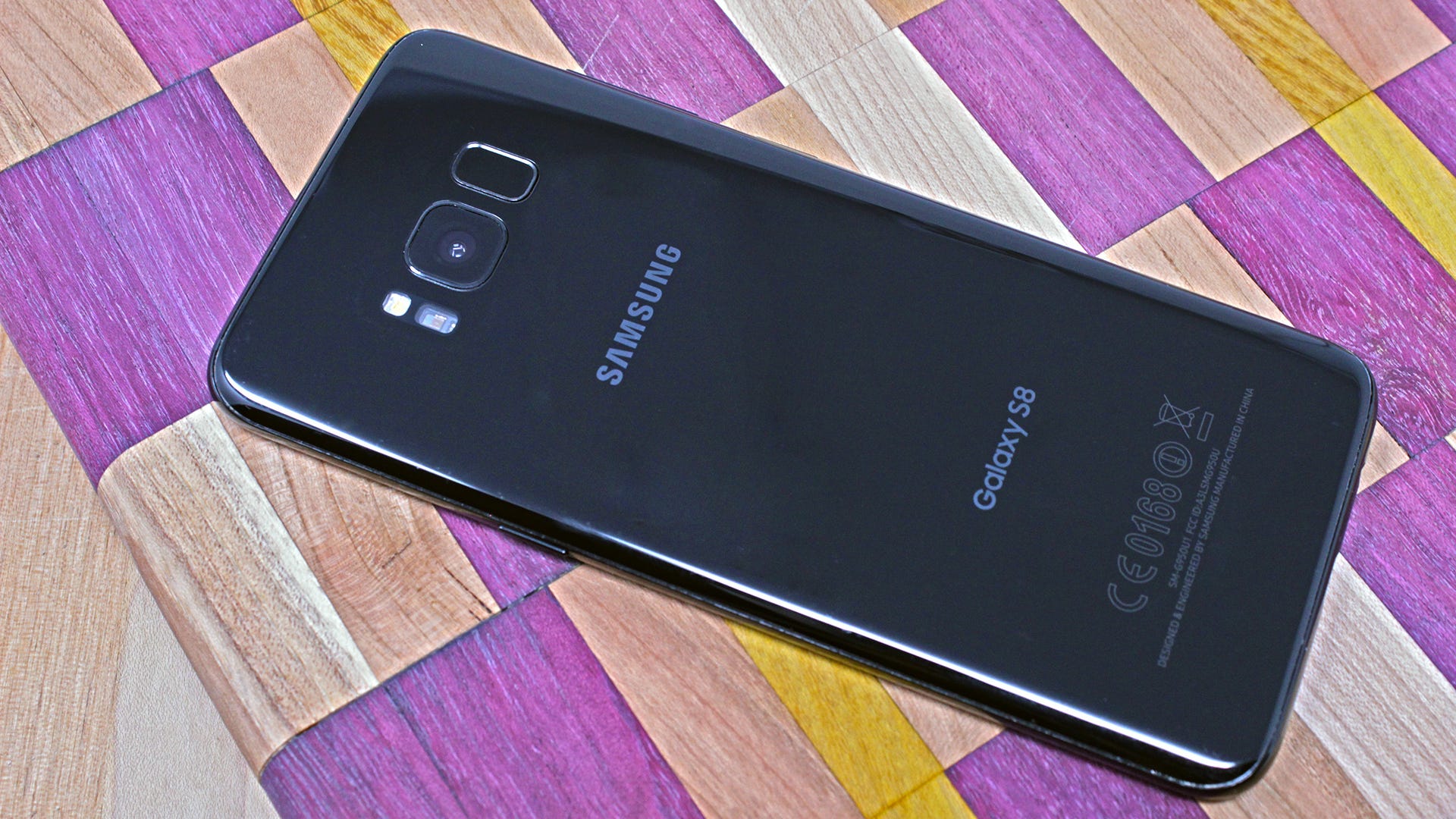 Samsung Galaxy S8 dengan latar belakang kayu kotak-kotak ungu