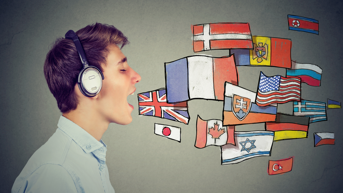 Một người đàn ông đeo tai nghe và miệng mở với nhiều lá cờ khác nhau dường như đang phát ra từ miệng, biểu thị nhiều ngôn ngữ nói khác nhau. 