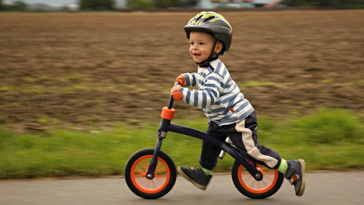 Ett barn som lär sig att cykla på en balanscykel