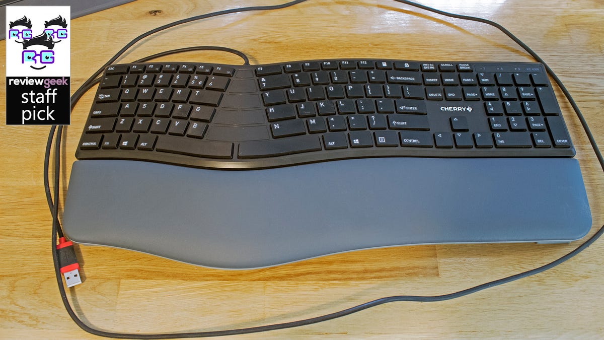 Keyboard ergonomis di atas meja kayu.