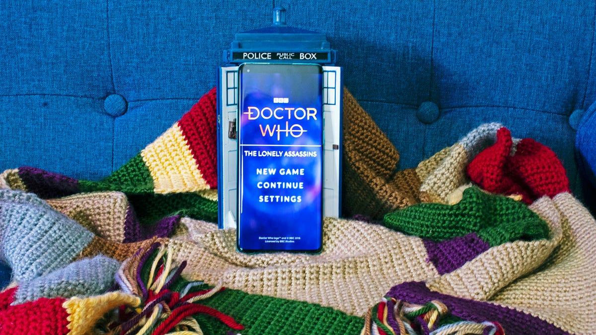 Một chiếc điện thoại có trò chơi "Doctor Who: Lonely Assassin" trước mặt Tardis và trên một chiếc khăn quàng cổ nhiều màu dài 12 foot.