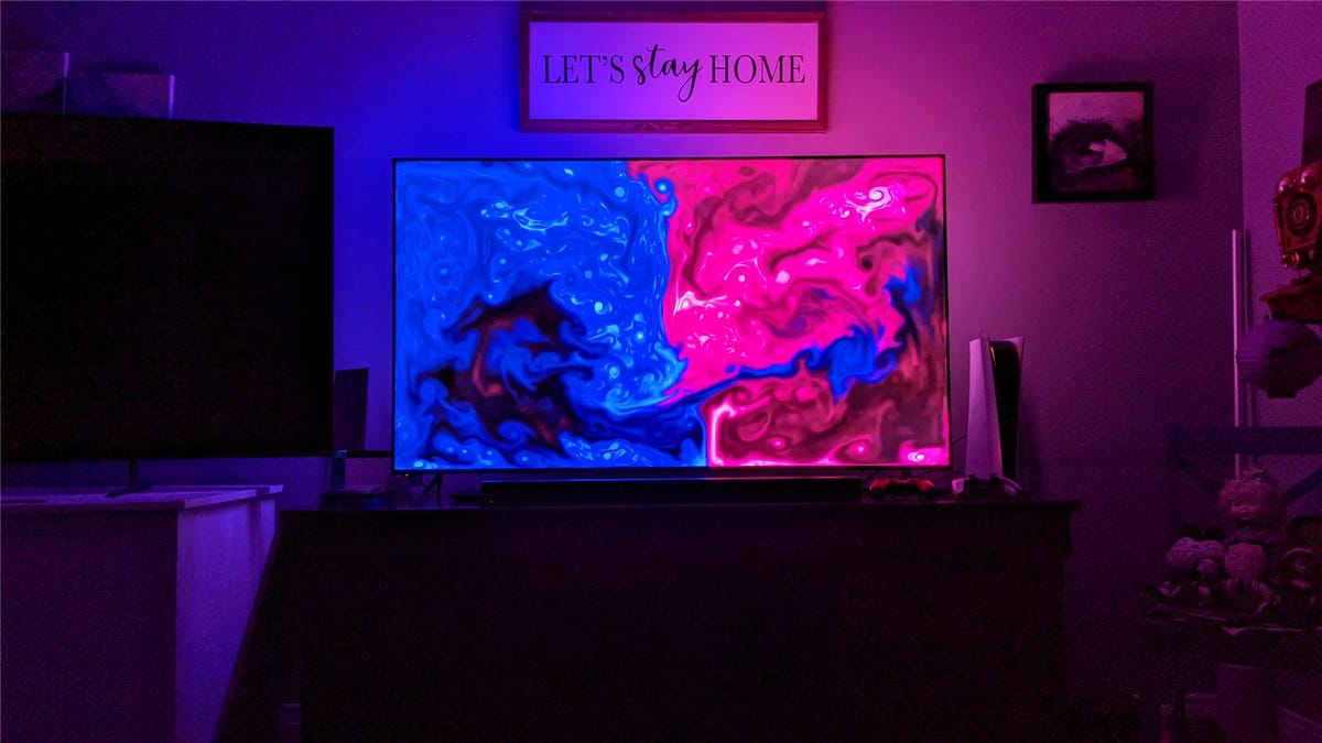 Philips Hue Gradient bersinar di tempat kerja, dengan separuh TV menunjukkan warna biru dan separuh lainnya berwarna merah muda