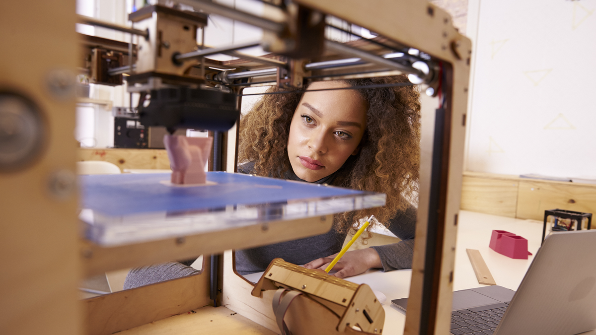 En kvinna använder en 3D-skrivare för att skapa en plastmodell.