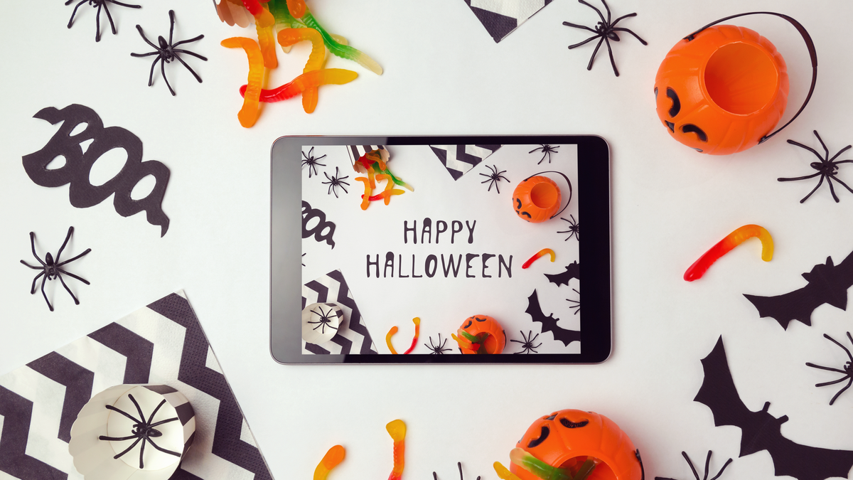 Latar belakang Halloween dengan tablet dan dekorasi digital