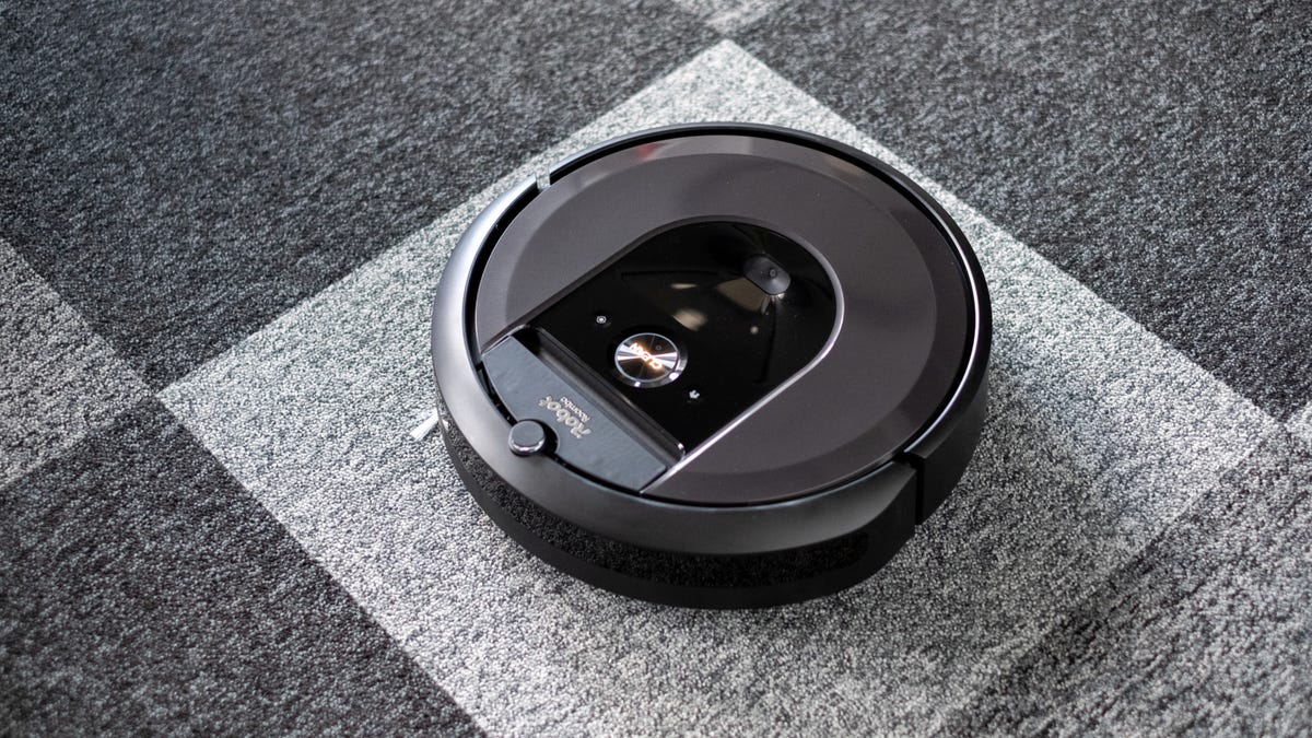 Một Roomba ở giữa tấm thảm có hoa văn hình vuông màu trắng và tối