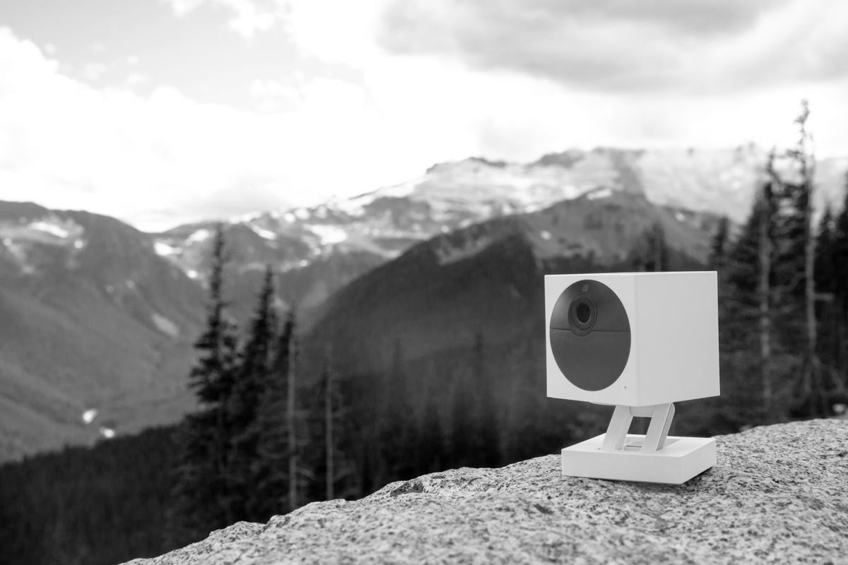 Foto hitam putih model Wyze Cam Outdoor di pegunungan.