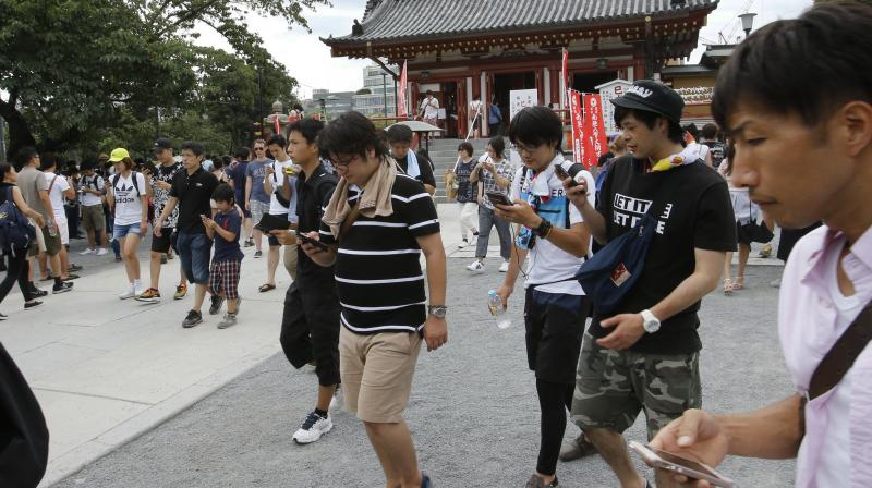 People play "Pokemon Go" in front of Kaneji Bentendo Buddhist temple at Ueno park in Tokyo. (AP Photo/Shizuo Kambayashi)