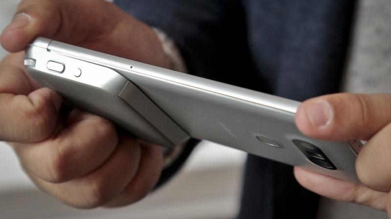 Bilden visar en hand som håller i kameran, längst ner till vänster, med fysiska knappar för att ta bilder och spela in videor med LG G5-smarttelefonen (Bild: AP)