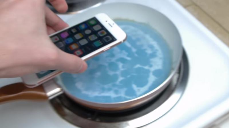 En man kastar en iPhone 6 i blått hett vax.  Varför?  Vi vet inte heller