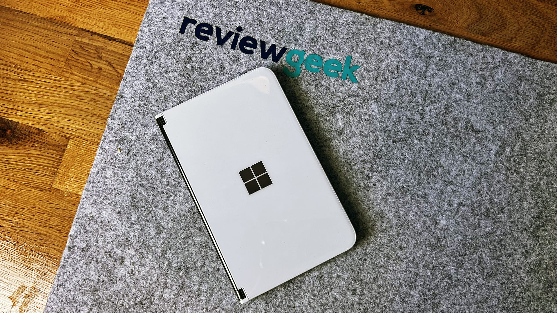 Surface Duo 2 mandiri di atas karpet dengan logo Review Geek