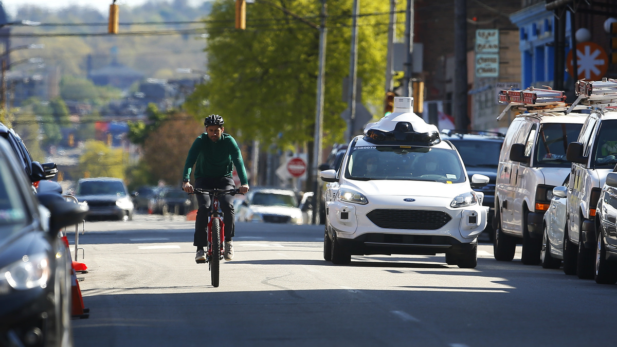 En cyklist bredvid en Argo självkörande bil.