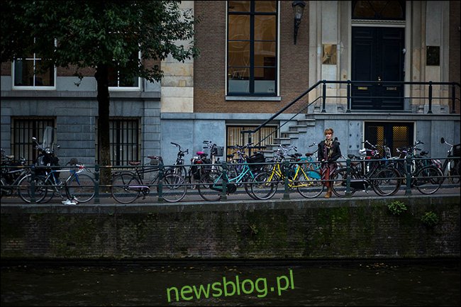 Một người phụ nữ đứng trên cầu phía sau một hàng xe đạp đang đỗ.