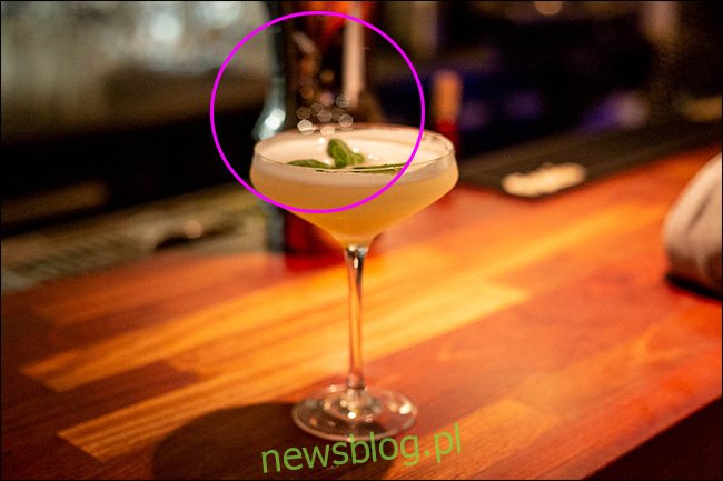 Ly cocktail trên quầy bar với hiệu ứng bokeh đa giác ở trung tâm. 