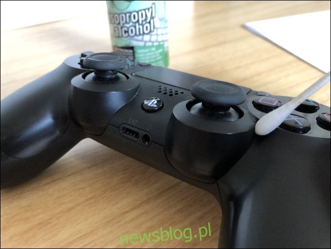 Bộ điều khiển DualShock 4 với chữ Q ở trên bên cạnh chai cồn isopropyl.
