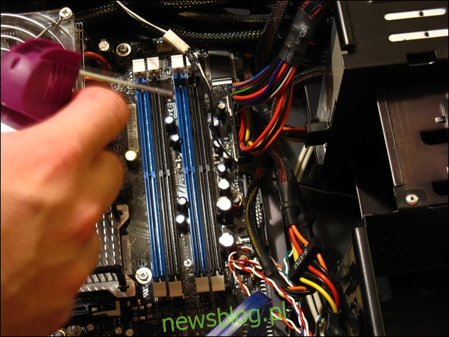 Một bàn tay cầm một lon khí nén trên vỏ máy tính đang mở. 