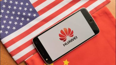 Telefon Huawei między flagą USA i Chin.