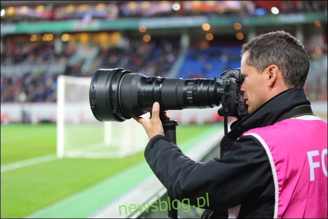 Nhiếp ảnh gia với ống kính zoom quang học lớn tại một trận đấu bóng đá.